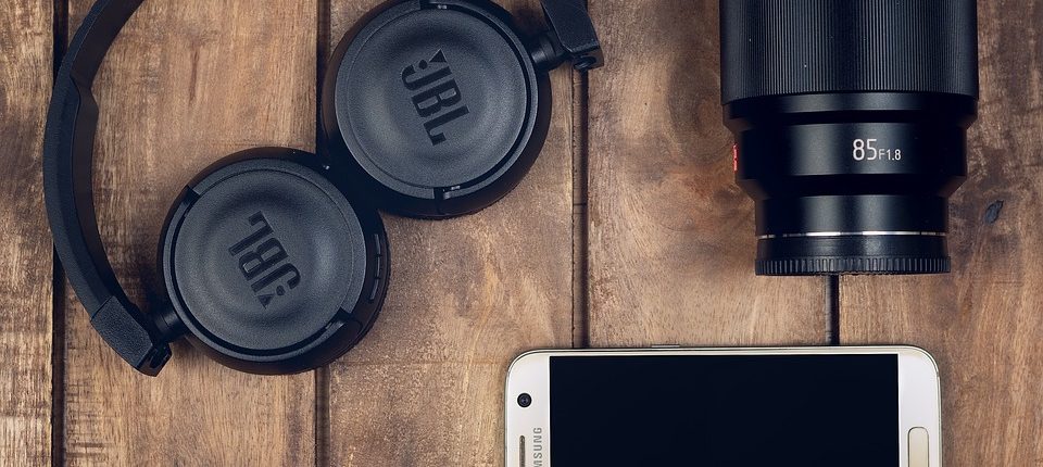 JBL Headphones mit Samsung Handy und Objektiv und USB Stick daneben